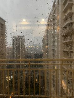 rain drops on the window as buildings stand in the background with skyscrapers behind them