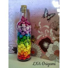 a bottle filled with lots of different colored rocks next to a butterfly wall paper bag