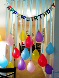 balloons and streamers are hanging from the ceiling in this birthday party decorating idea