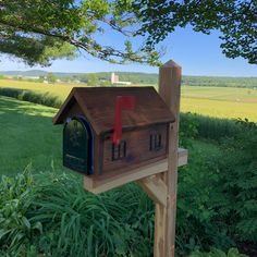 a wooden mailbox sitting in the middle of a lush green field