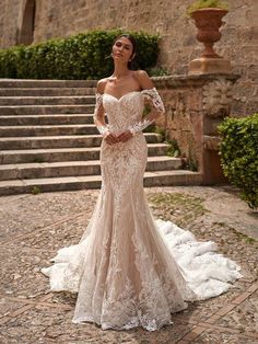 a woman standing in front of some steps wearing a dress with an off the shoulder design