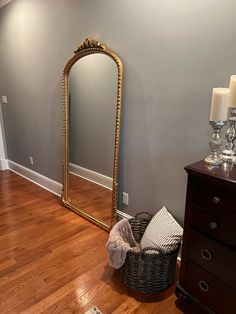 a large gold framed mirror sitting on top of a wooden floor next to a dresser