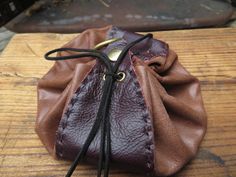 These leather pouches are similar to our simple leather pouch, but  we have added more.  These pouches have gromets in all the holes for the cord to slide smoothly. There is a hand stitched strap from the front across the bottom to the back. A hand stitched on strap on the back that fits most belts so you can carry it hands free. A snap button on top for easy top access. And a brass loop on the top, great for hanging this pouch with a carabineer (not included) or any hook. The cord is long enoug Hand-stitched Brown Coin Purse For Daily Use, Leather Hand-stitched Coin Purse For Everyday Use, Brown Hand-stitched Coin Purse For Daily Use, Hand-stitched Leather Coin Purse For Daily Use, Leather Drawstring Pouch, Brown Leather Pouch With Pockets, Artisan Hand-tooled Pouch Bag, Vintage Brown Leather Pouch, Hand-stitched Brown Leather Coin Purse