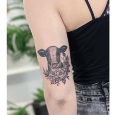 a woman's arm with a cow and flowers tattoo on the left side of her arm