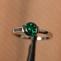 It is a lab emerald ring. The main stone is 7 mm*7 mm round cut.weight about 1.30 carats.The basic metal is sterling silver and plated with rhodium/14k white  gold/14k rose gold/14k yellow goldYou can also go to my shop Home for more elegant rings: https://www.etsy.com/shop/godjewelry?ref=hdr_shop_menu Customization is always welcome and please feel free to contact with me if you have any design ideas! Classic Round Emerald Ring With Tension Setting, Classic Emerald Ring With Round Stone For Anniversary, Classic Round Emerald Promise Ring, Emerald Round Band Ring For May Birthstone Anniversary, May Birthstone Solitaire Ring With Round Cut, White Gold Solitaire Ring For May Birthstone, May Birthstone Jewelry With Tension Setting For Anniversary, Classic Silver Emerald Birthstone Ring, Sterling Silver Emerald Ring With Round Stone