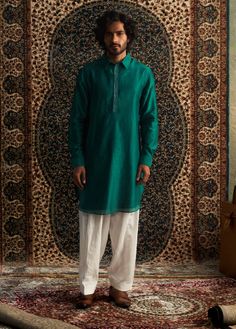 This emerald green pathani kurta set is a stunning choice for festive occasions like mehendi. The subtle embroidery on the placket adds a touch of elegance without being over the top. Paired with a coordinating salwar in a color-on-color design, it strikes the perfect balance between traditional and stylish. This set is sure to become a go-to piece in your wardrobe for celebrating special moments! Male Model Shoot Ideas, Green Sherwani With Dupatta, Straight Kurta Style, Male Model Shoot, Model Shoot Ideas, Green Kurta Men, Traditional Green Jamawar Kurta, Ceremonial Green Kurta With Naqshi Detailing, Green Colour Kurta For Men, Subtle Embroidery