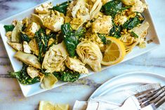 a white plate topped with pasta and veggies next to a knife and fork