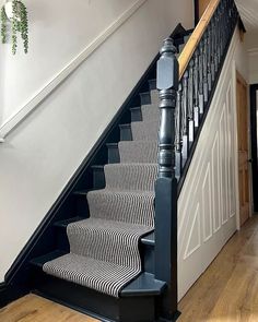 a staircase with black and white striped carpet next to a light on top of the stairs