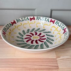 a colorful bowl sitting on top of a wooden table next to a white door with red, yellow and green designs