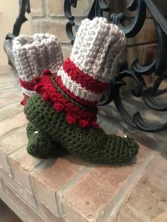 a pair of crocheted slippers sitting on top of a brick floor next to a fireplace