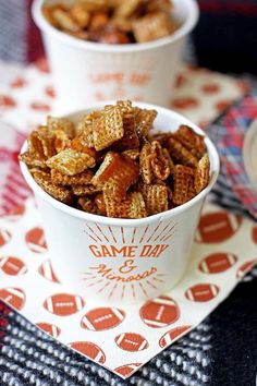 two cups filled with cereal sitting on top of a red and white table cloth next to each other