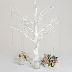 two vases with flowers are next to a white tree that has chains hanging from it