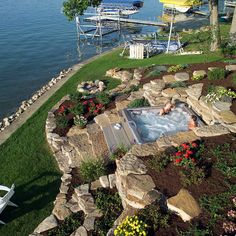 a hot tub sitting on top of a lush green hillside next to a body of water