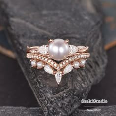 a pearl and diamond ring sitting on top of a rock