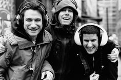 three men with headphones on walking down the street