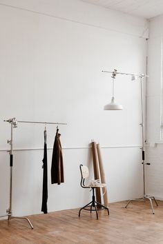 an empty room with clothes hanging on the wall and a chair in front of it