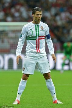 a man standing on top of a soccer field wearing a white shirt and red shoes