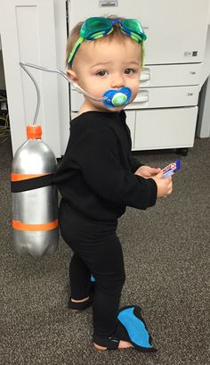 a young child with a pacifier in his mouth standing next to a water bottle