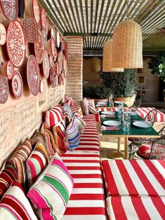 an outdoor seating area with red and white striped cushions on the tables, plates hanging from the ceiling