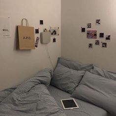 a laptop computer sitting on top of a bed in a room with white walls and blue sheets