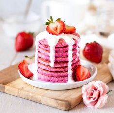 a stack of strawberry shortcakes with icing and strawberries on the side