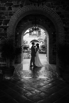 a bride and groom standing under an archway