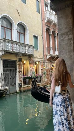 a woman standing next to a gondola on a canal