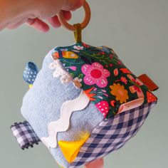 a hand holding a small blue and white patchwork doll with a key chain attached to it