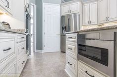 a kitchen with white cabinets and stainless steel appliances