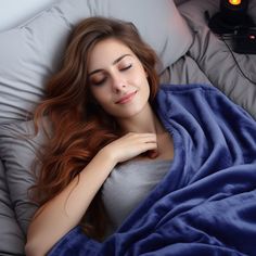 a woman laying in bed under a blue blanket