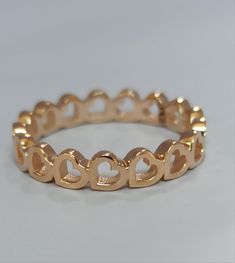 a gold ring with hearts in the middle on a white surface, it is made out of