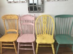 four different colored chairs lined up against a wall