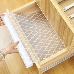 a person is wrapping up a piece of paper on the floor next to a drawer