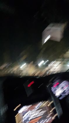 blurry image of cars driving down the road at night time with buildings in the background