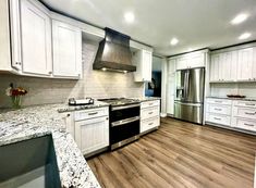 an empty kitchen with white cabinets and wood flooring is pictured in this image from the front view