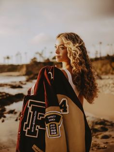 a woman is standing on the beach with her back to the camera and she has a backpack in her hand