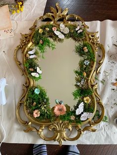 a mirror that is sitting on top of a table with flowers and leaves around it