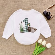 One Lucky Duck Birthday Romper, Mallard Duck Birthday Baby Romper, Duckling Bodysuit,  Romper Sweatshirt, Trending Animal Shirt - Handmade  - Ships from USA  - Materials: 100% CPSIA Compliant and Ethically Made material Light fabric (5.0 oz/yd² (170 g/m  Crafted with soft, breathable fabric, this romper ensures your baby stays comfortable through playtimes and nap times alike. Featuring charming designs suitable for all babies, our romper is as adorable as it is practical.  Quick Sizing Tip  Our Crew Neck Top With Cartoon Print For First Birthday, Long Sleeve Tops With Cartoon Print For Birthday, Long Sleeve Tops With Graphic Print For Birthday, Playful Cartoon Print Tops For First Birthday, Family Matching Long Sleeve Tops With Character Print, Playful Tops With Cartoon Print For First Birthday, Long Sleeve Cartoon Print T-shirt For Birthday, Long Sleeve T-shirt With Cartoon Print For Birthday, Graphic Print Long Sleeve Top For First Birthday