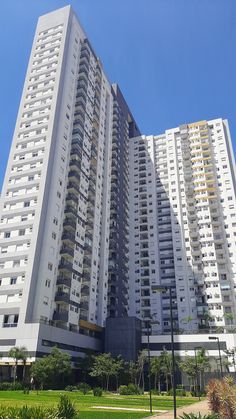 a tall white building sitting next to a lush green park