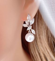 a close up of a pair of earrings on a woman's ear with white pearls