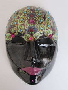 "* This very sturdy paper mache mask is meant for wearing and will fit most adults. It can also be hung on the wall by the ribbon in back. An elastic band is included to attach to the side holes if you wish to wear this on Mardi Gras or to a masquerade party. * The back is painted black and the front, back and edges have 3 layers of varnish. The eyes and entire edge of the mask are rimmed with gold cord . * Multiple paisley designs adorn the forehead with dozens of blue gems accenting various areas.  The black face and purple lips really accentuate the paisley. * Measures 8 3/4\" x 6\" FREE SHIPPING to the Continental United States only" Handmade Black Carnival Masks And Prosthetics, Handmade Black Masks And Prosthetics For Carnival, Hand Painted Black Masquerade Mask, Hand Painted Black Mask For Masquerade, Handmade Black Masks For Carnival, Artistic Black Masks And Prosthetics For Mardi Gras, Black Masks For Masquerade Festivals, Artistic Handmade Black Masks, Traditional Black Masks And Prosthetics For Carnival