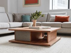 a living room with a couch, coffee table and books on the floor in front of it