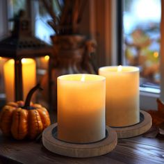 two white candles sitting on top of a wooden table next to pumpkins and other decorations