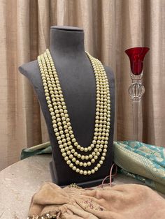 We are proud of our prestigious heritage in this 4 strand pearls groom mala for the bridegroom! A necklace that upholds traditions is royal and elegant. Perfect for the grooms to pair with their sherwanis. Details: Length of Necklace-14.5 Inches All products are manufactured using traditional skills from our rich heritage of crafts.  The process of these crafts is essentially manual. Hence, any irregularities or variations are an inherent part of these handcrafting processes. Festive Pearl Chain Necklace For Reception, Festive Pearl Necklace For Reception, Pearl Chain Necklace For Reception, Pearl Bridal Necklace For Reception During Diwali, Pearl Bridal Necklace For Reception At Diwali, Traditional Pearl Necklace For Reception, Festive Kundan Pearl Necklace For Reception, Bollywood Style Pearl Chain Necklace For Celebrations, Festive Gold Beads For Wedding