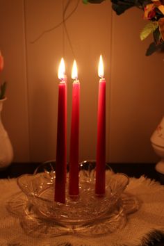 three red candles sitting on top of a glass plate