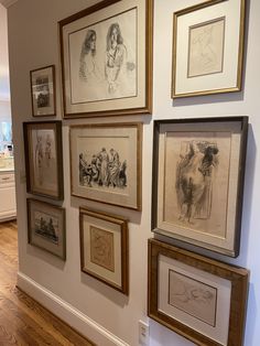 a wall with many framed drawings on it