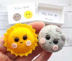 two small felt sun and moon brooches are shown in front of each other