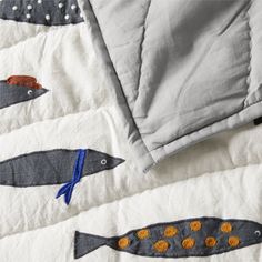 a quilted bed spread with fish and dots on it's edges, next to a pillow