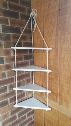 a white shelf hanging from the side of a brick wall