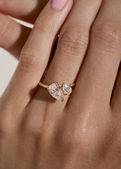 a woman's hand with a gold ring and two pear shaped diamonds on it